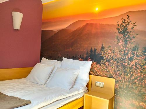 a bed in a room with a painting on the wall at Willa STRITZKI in Wisła