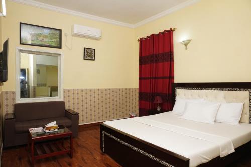 a bedroom with a bed and a chair in a room at ORION INN Guest House F-7 Islamabad in Islamabad