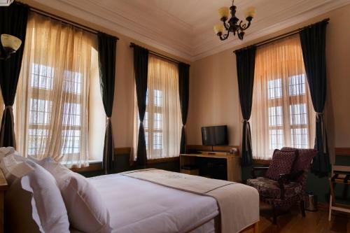 - une chambre avec un lit, une chaise et des fenêtres dans l'établissement Kocanli Kosku, à Dikili