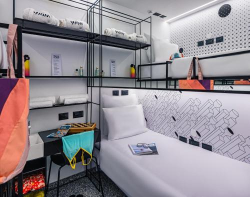 a room with a large white bed and shelves at Wom Allenby Pod Hotel - a member of Brown Hotels in Tel Aviv