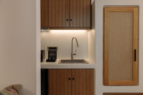 a kitchen with a sink and wooden cabinets at "Makava Suites" Your Luxe Urban Sanctuary in Naxos Chora