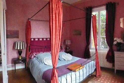 - une chambre avec un lit à baldaquin et des rideaux rouges dans l'établissement Villa Thomas, à Arcachon