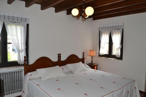 a bedroom with a bed with white sheets and windows at Casa Fidel in Fontanina