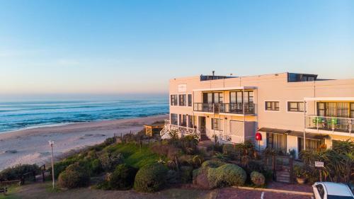 an apartment building on the beach with the ocean at On the Beach Guesthouse Jeffreys Bay in Jeffreys Bay
