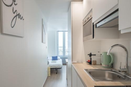 - une cuisine avec des placards blancs et un évier dans l'établissement Lavie Maison Paris AC Retreat, à Paris
