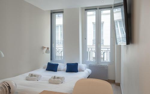 Elle comprend un grand lit blanc avec des oreillers bleus. dans l'établissement Lavie Maison Paris AC Retreat, à Paris