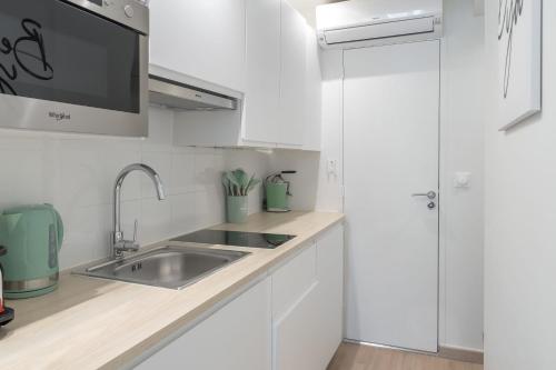 une cuisine avec des armoires blanches et un évier dans l'établissement Lavie Maison Paris AC Retreat, à Paris