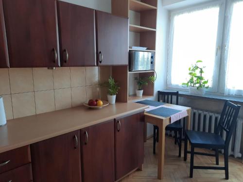 a kitchen with wooden cabinets and a table with a bowl of fruit at Travel Apartament Cracow in Kraków