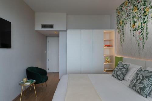 a bedroom with a white bed and a green chair at Olivi Hotel & Natural Spa in Sirmione