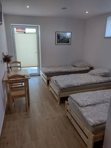Cette chambre comprend 3 lits, une table et une chaise. dans l'établissement Villa na Chabrowej, à Miedziana Góra