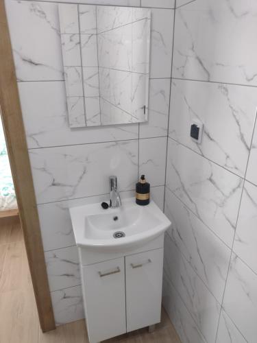 W białej łazience znajduje się umywalka i lustro. w obiekcie Villa na Chabrowej w mieście Miedziana Góra