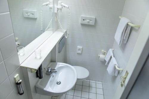 a white bathroom with a sink and a toilet at ACHAT Hotel Suhl in Suhl