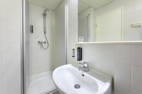 a white bathroom with a sink and a shower at ACHAT Hotel Suhl in Suhl
