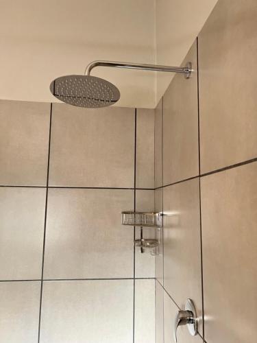 a shower with a glass door with a shower head at Tuinhuis in Oudtshoorn