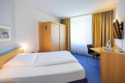 a hotel room with a bed and a desk at ACHAT Hotel Suhl in Suhl