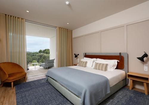 um quarto com uma cama grande e uma varanda em Montebelo Aguieira Lake Resort & Spa em Mortágua