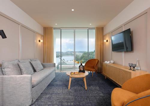 a living room with a couch and a tv at Montebelo Aguieira Lake Resort & Spa in Mortágua