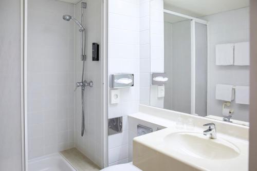 a white bathroom with a sink and a shower at ACHAT Hotel Suhl in Suhl