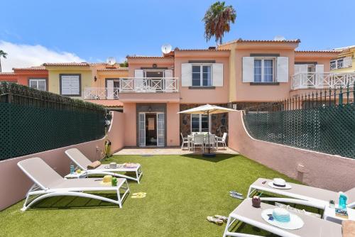 a house with a yard with lawn chairs and a fence at Chalet Santa Ana 24 by VillaGranCanaria in Playa del Ingles