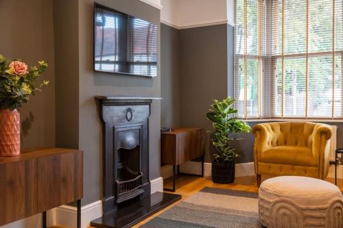 a living room with a fireplace and a chair at Clifton Villa By RentMyHouse in Hereford