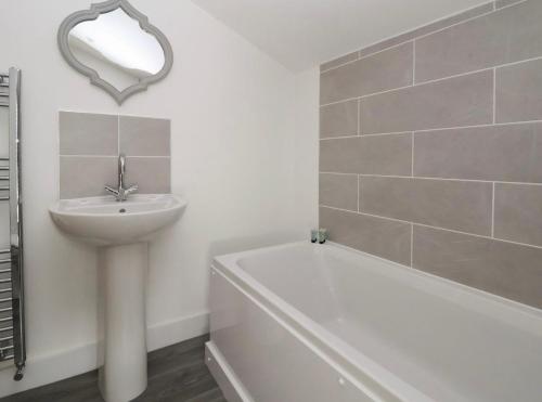 La salle de bains blanche est pourvue d'un lavabo et d'une baignoire. dans l'établissement Hillside, à Conwy