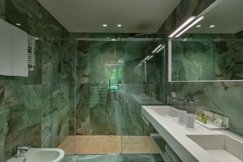 a bathroom with two sinks and a glass shower at Olivi Hotel & Natural Spa in Sirmione