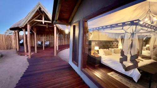 a bedroom with a canopy bed on a deck at Kalahari Red Dunes Lodge in Kalkrand