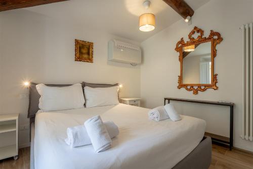 een slaapkamer met een groot wit bed en een spiegel bij Piazza Dei Rossi Due View in Florence