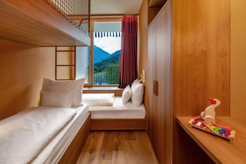 a small bedroom with two beds and a window at Falkensteiner Family Hotel Montafon - The Leading Hotels of the World in Schruns