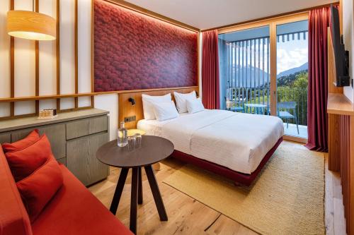 ein Hotelzimmer mit einem Bett, einem Tisch und einem Sofa in der Unterkunft Falkensteiner Family Hotel Montafon - The Leading Hotels of the World in Schruns-Tschagguns