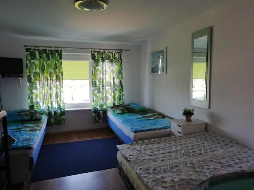 two beds in a room with two windows at Pokoje przy fontannie in Karwia