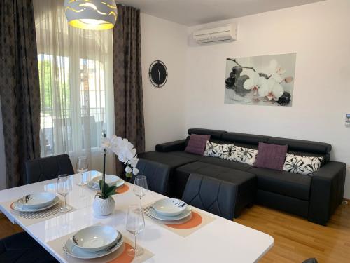 ein Wohnzimmer mit einem Tisch und einem Sofa in der Unterkunft Apartmani Villa Lavanda II in Brodarica