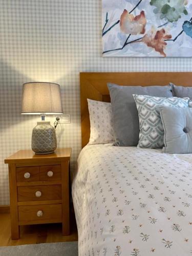 1 dormitorio con 1 cama y 1 mesa con lámpara en Andainas Apartamentos Turísticos A en Milladoiro