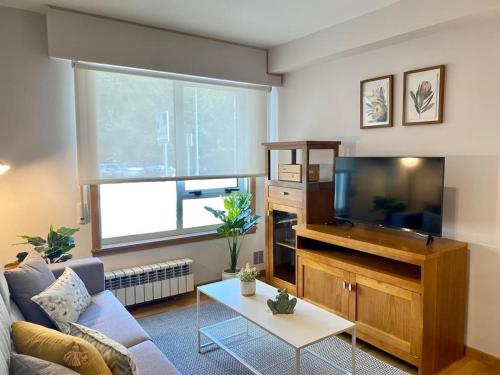 Andainas Apartamentos Turísticos A في ميلادوريو: غرفة معيشة مع أريكة وتلفزيون بشاشة مسطحة
