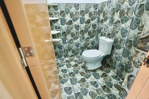 a bathroom with a toilet and a tiled wall at Peaceful and Calm place in Lucena