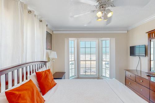 a bedroom with a bed with orange pillows and a television at Beachfront Haven in Galveston