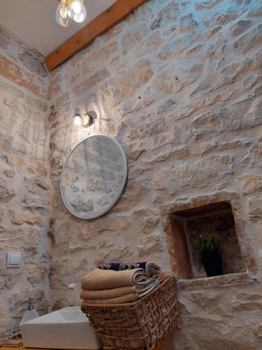 een badkamer met een stenen muur met een spiegel en een mand bij Apartment Anda in Drinovci