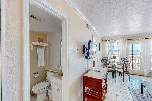 a bathroom with a toilet and a table with chairs at Beachfront Haven in Galveston