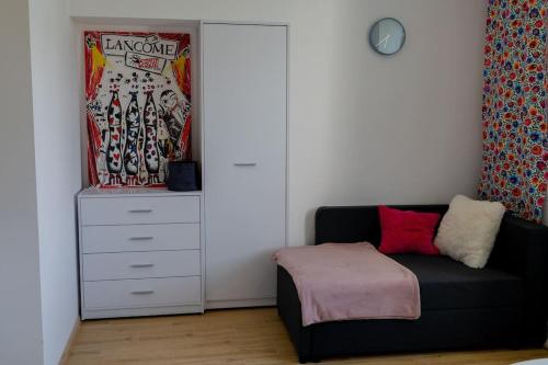 1 dormitorio con sofá negro y cómoda blanca en Studio z widokiem na rzekę, en Przemyśl