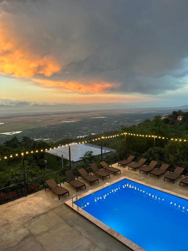 a swimming pool with lounge chairs and a sunset at Boutique Hotel BelleVue in Sighnaghi