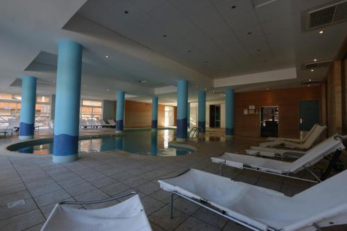 a large lobby with chairs and a swimming pool at Terrasses de Labrau - piscine in Allos