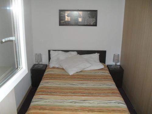 Bett in einem Zimmer mit zwei Lampen und einem Fenster in der Unterkunft Terrasses de Labrau - Res piscine in Allos