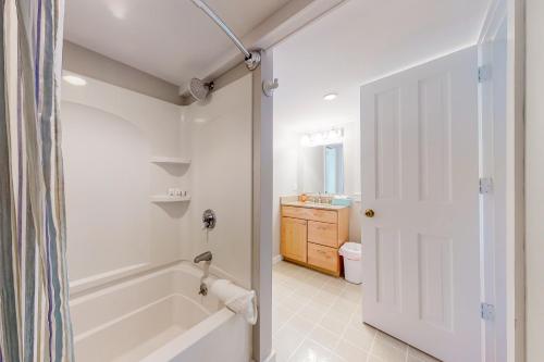 ein weißes Badezimmer mit einer Badewanne und einem Waschbecken in der Unterkunft Herman Vincent House in Edgartown