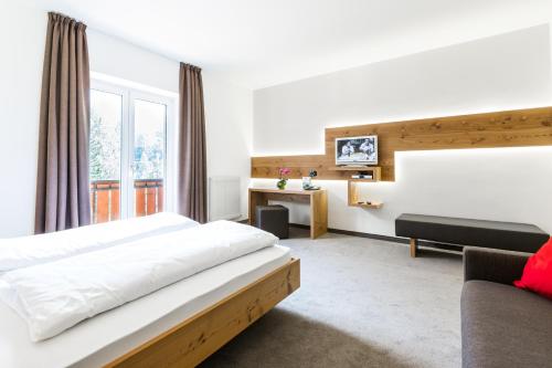 um quarto de hotel com uma cama e um sofá em Zur Mühle Wohlfühloase em Trodena