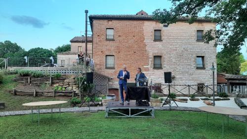 two men standing on a stage in front of a building at Bed & Breakfast Villa Monterosso in Sassoferrato