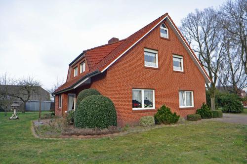 a red brick house with a red roof at Ferienwohnung Bohlen 65265 in Moormerland