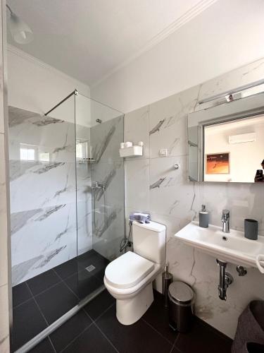 a bathroom with a toilet and a sink and a shower at Meto Rooms in Sarandë
