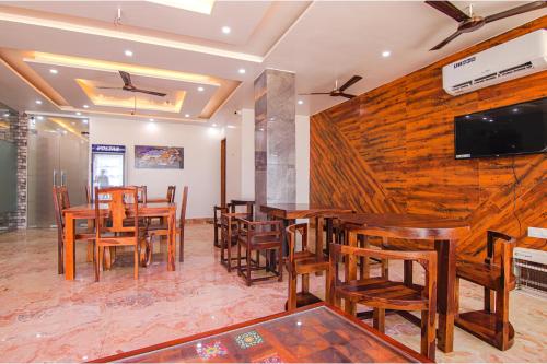 a restaurant with wooden tables and chairs and a flat screen tv at FabHotel Meridian Inn in Mohali