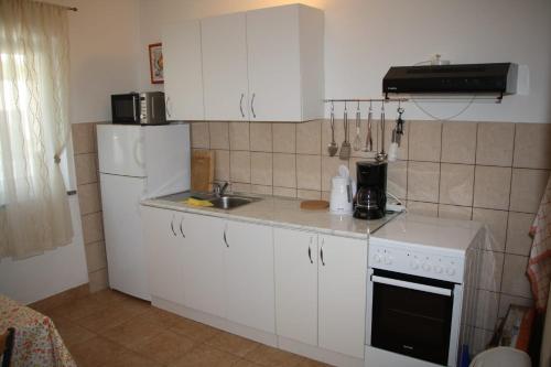 a kitchen with white cabinets and a sink and a refrigerator at Apartman Mara in Sveti Juraj