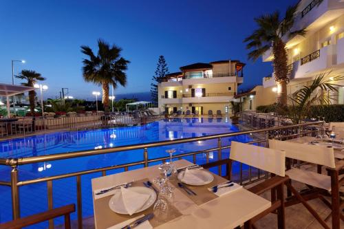 - Vistas a la piscina de un complejo con mesas y sillas en Despina Aparthotel by Philoxenia Hotel & SPA, en Malia